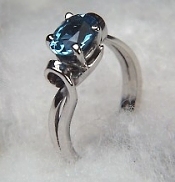 Oval blue topaz ring in simple scroll mounting